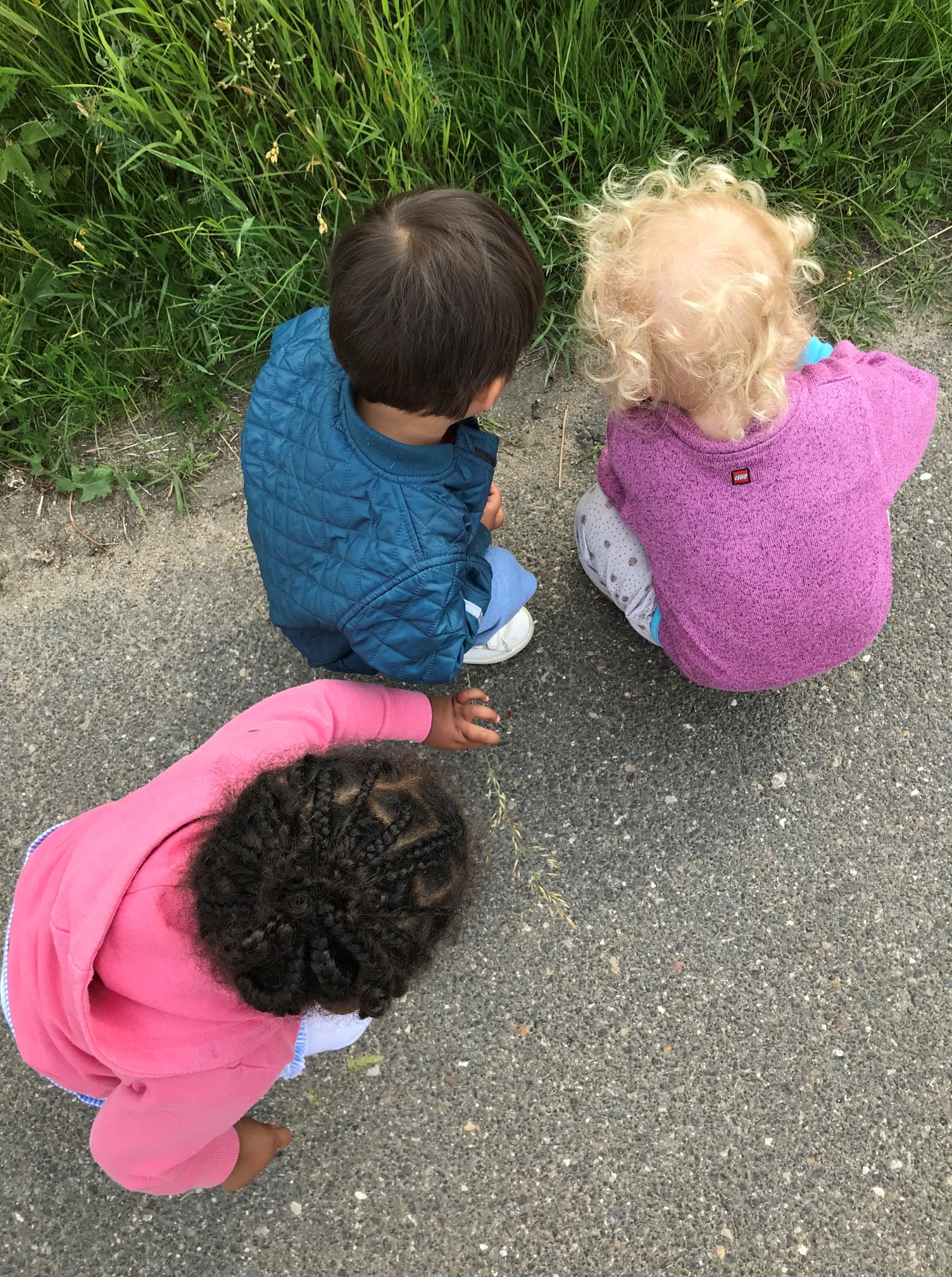 Tre børn på tur, som sidder og kigger på noget de har fundet